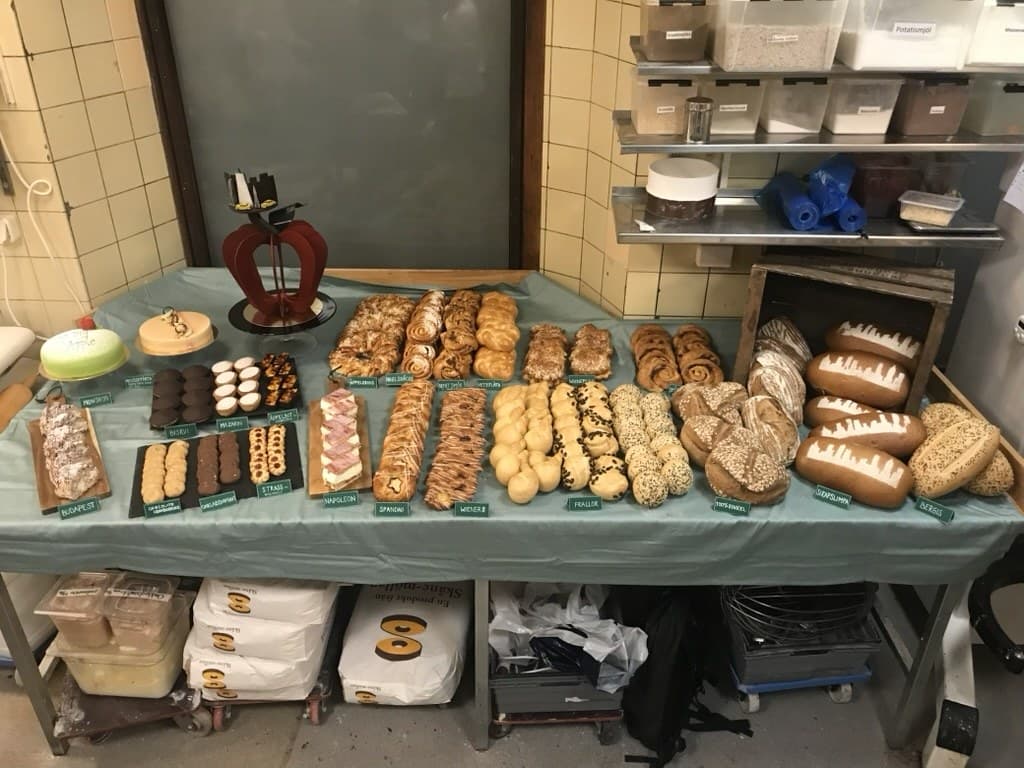 Emelia Asplunds uppdukade bord i Tössebageriets bakverkstad, med chokladäpple, prinsesstårta, bakelser, wienerbröd och bröd med New Yorks skyline på skorpan