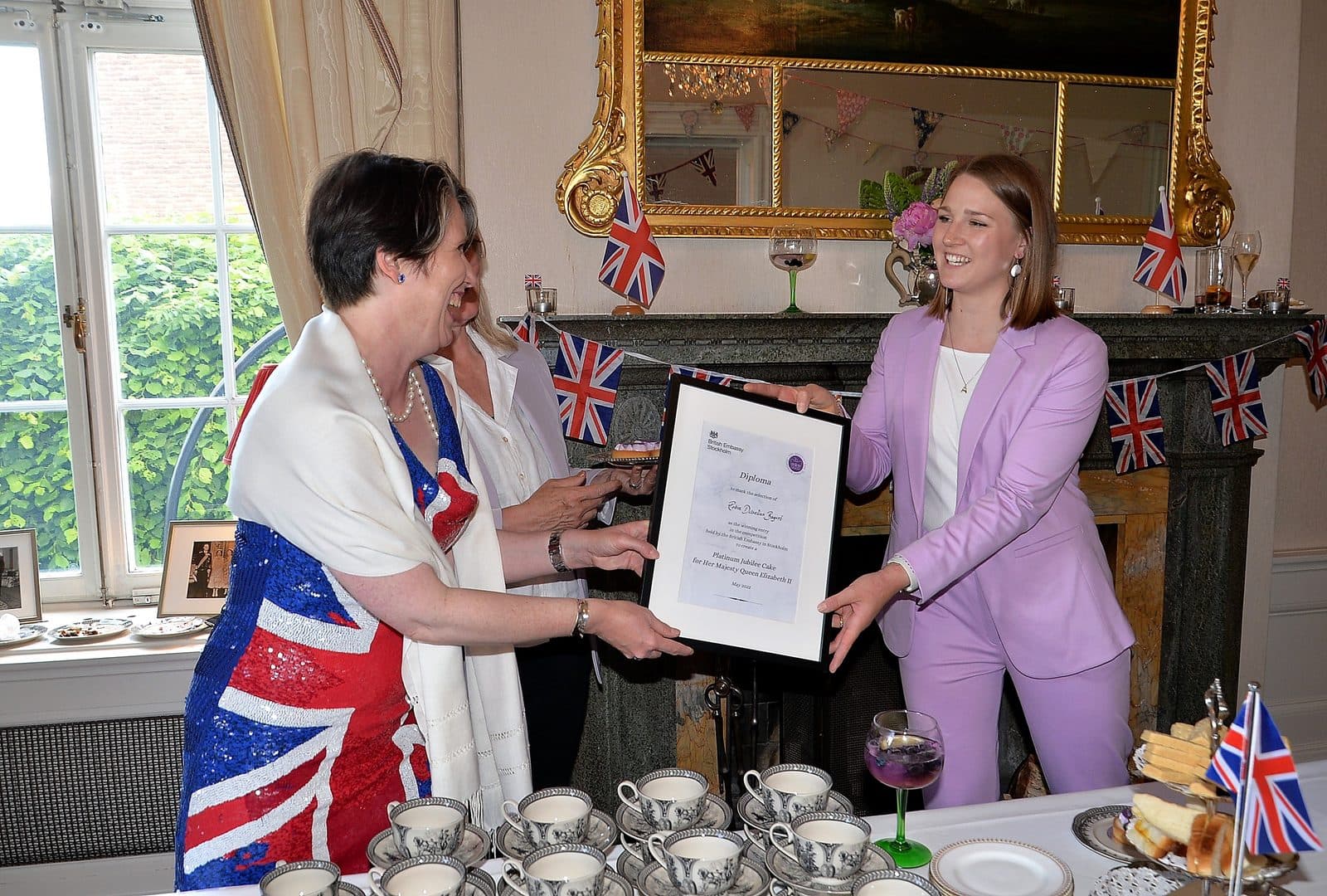 Emelia Asplund tar emot diplomet från brittiska ambassaden i Stockholm, i ett rum klätt i brittiska flaggor